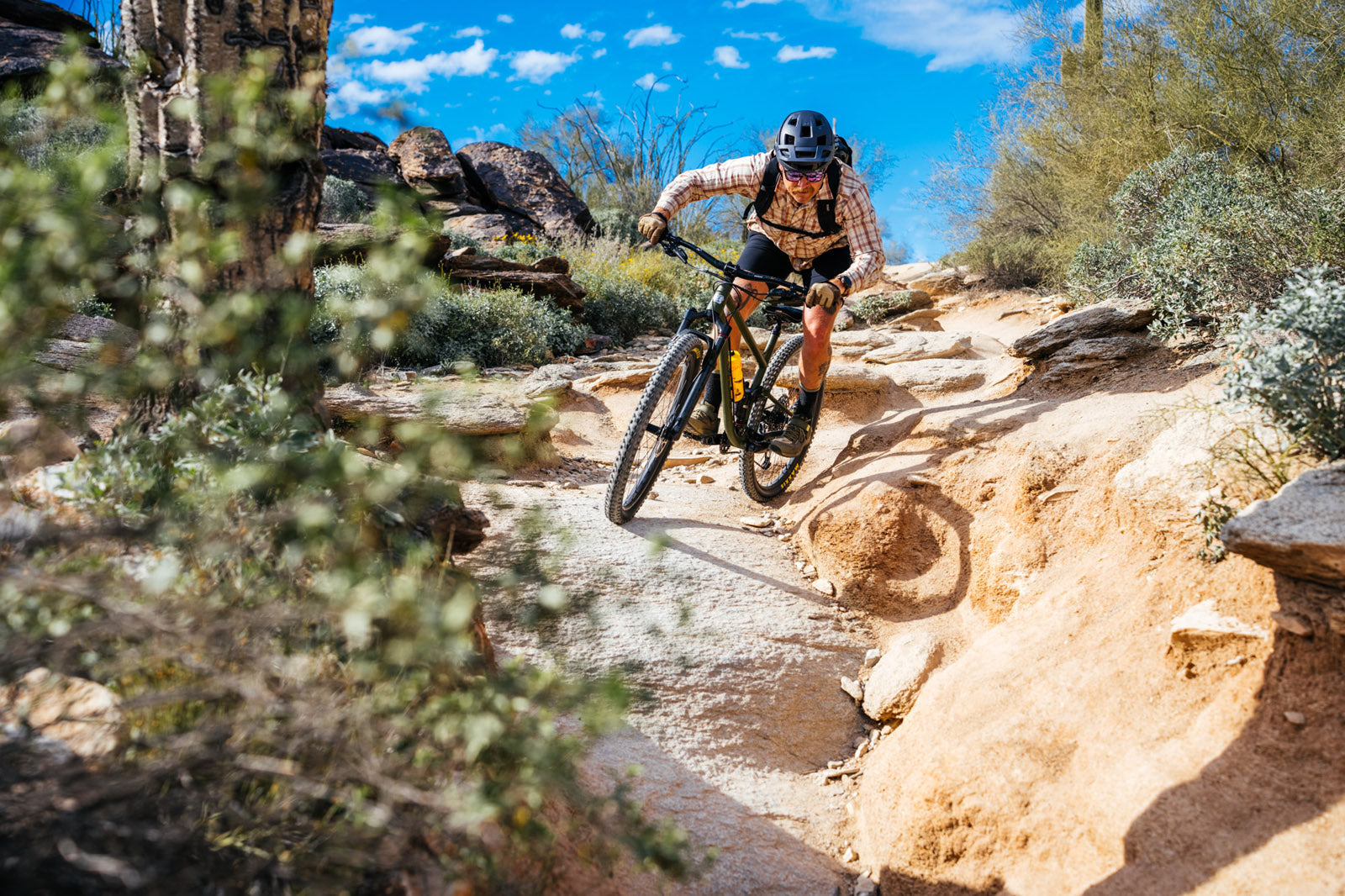 Person mountain biking on a rocky trail with desert landscape